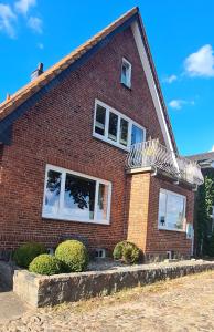 a red brick house with white windows and bushes at Exklusive Ferienwohnung Strohberg in Plön