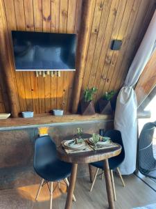 a room with a table and two chairs and a tv at DChalé in Japaratinga