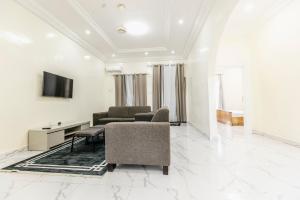 un salon avec un canapé et une télévision sur un mur dans l'établissement Serenity Apartments, à Old Yundum