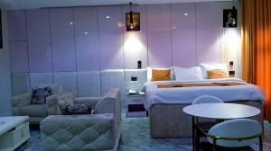 a hotel room with a bed and a table and chairs at Uptown Life Hotel and Suites in Warri