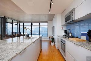 a kitchen with white counter tops and a view of the ocean at Spacious 2BD in Vancouver Patio with Ocean View in Vancouver +26 photos
