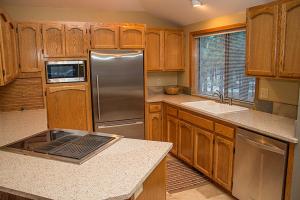 a kitchen with wooden cabinets and a stainless steel refrigerator at Sunriver Vacation House in Sunriver