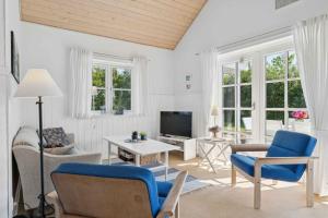 a living room with blue chairs and a tv at Peaceful Cottage In Scenic Surroundings in Højsand
