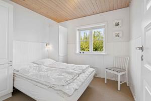 a white bedroom with a bed and a window at Peaceful Cottage In Scenic Surroundings in Højsand