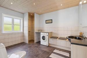 a bathroom with a washing machine and a sink at Peaceful Cottage In Scenic Surroundings in Højsand +7 photos