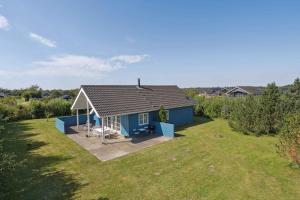 a small blue house in a field with a yard at Peaceful Cottage In Scenic Surroundings in Højsand