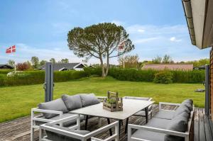 a patio with a table and chairs and a tree at Family-Friendly Activity House By The Sea in Frederikshavn