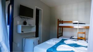 a bedroom with a bed with a television and a bunk bed at POUSADA e HOSTEL ARAUNA in Cabo Frio