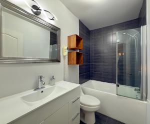 een badkamer met een wastafel, een toilet en een spiegel bij Refuge Urbain Quebec - Loft Bonséjours in Québec