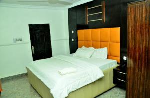 Un dormitorio con una cama grande con cabecero naranja. en Flogate Hotel, en Enugu