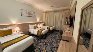 a hotel room with two beds and a television at New Level Hotel Bathaa Quraish in Mecca