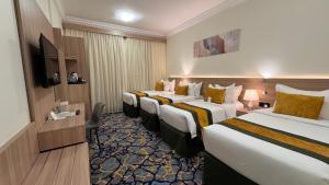 a hotel room with three beds and a television at New Level Hotel Bathaa Quraish in Mecca