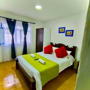a bedroom with a large bed with two red pillows at Hostal Villa del Sol in Salento