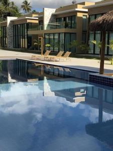 a swimming pool with chairs and a building at Casa Milagres Morada do Toque l até 6 adultos in São Miguel dos Milagres