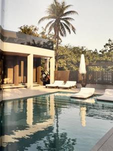 a swimming pool with a house and a palm tree at Villa Golfinho Luxury in Praia do Carvoeiro