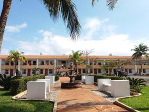 ein Gebäude mit einem Innenhof mit weißen Stühlen und Palmen in der Unterkunft Hotel Torre Molino in Monte Gordo