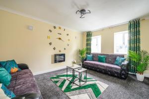 a living room with a couch and a clock on the wall at H17A Cosy & Welcoming home in Liversedge