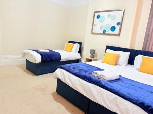 a bedroom with two beds with blue and yellow pillows at 1 Bed Flat - Sleeps 5 - Parking - Wifi in Leicester +2 photos