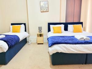 a bedroom with two beds with blue and yellow pillows at 1 Bed Flat - Sleeps 5 - Parking - Wifi in Leicester