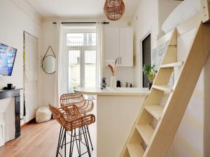 a kitchen with a staircase and two chairs in a room at Charming Studio 1BR-2P - Batignolles in Paris +4 photos