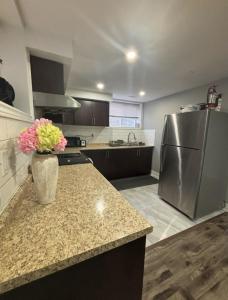 a kitchen with a refrigerator and a counter with a vase of flowers at Fully Furnished 2 Bedroom Apartment in Kitchener
