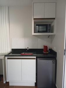 a kitchen with white cabinets and a microwave at Solar Curitiba Suites in Curitiba