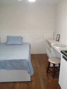 a small white bedroom with a bed and a stool at Solar Curitiba Suites in Curitiba