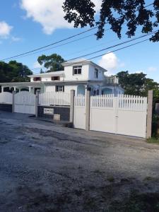a white fence in front of a white house at Résidence LE LATANIER in Sainte-Anne