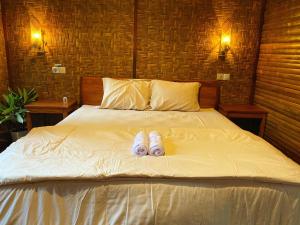 a pair of slippers laying on a bed at Tetebatu FLOWER in Tetebatu