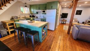 a kitchen with green cabinets and a blue island with bar stools at L'Ancestrale spa, vue, salle d'arcades in La Malbaie