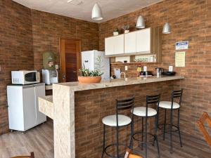a kitchen with a bar with stools at a counter at Atalaia Suítes in Salinópolis