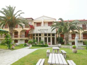 a building with benches in front of it with palm trees at Asteras hotel in Hanioti