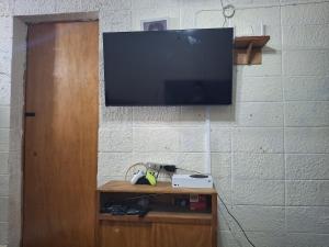 a flat screen tv hanging on a brick wall at Backpacker's ROOF in San Salvador