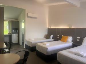 una habitación de hotel con dos camas y una mesa en Fern Bay Motel, en Newcastle