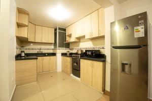 a kitchen with wooden cabinets and a stainless steel refrigerator at Departamento para 14 personas Cusco in Cusco +25 photos