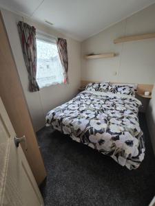 a bedroom with a bed with a black and white comforter at Superb 8 Berth Caravan At St Osyth Beach, Essex Ref 28001G in Jaywick Sands +13 photos