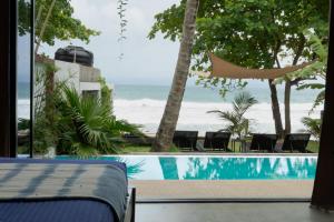 a bedroom with a view of the beach and a swimming pool at Parasol dore in Dickwella