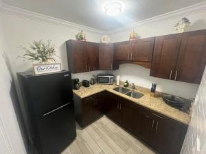 タンパにあるEl Palacioの木製のキャビネットと黒い冷蔵庫を備えたキッチン +8枚の写真