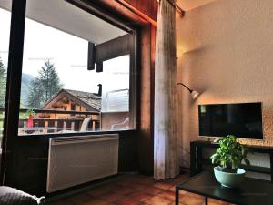 a living room with a large window and a tv at Charmant studio 4 pers. au Grand-Bornand, centre du village - FR-1-458-254 in Le Grand-Bornand