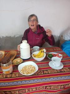 an older woman sitting at a table with food at Hotel INKAS WATANA LODGE in Acora