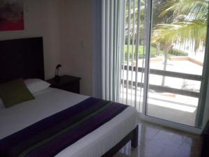 a bedroom with a bed and a large sliding glass door at MoonLight Condos in Puerto Morelos