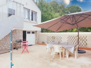a patio with a table and chairs and an umbrella at Gîte Saint Lubin à Cloyes : Confort familial et charme régional - FR-1-581-157 in Cloyes-sur-le-Loir