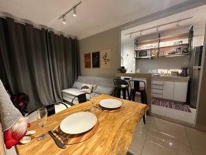 a living room with a wooden table and a kitchen at Flats Praia Uberlandia - Apt próximo ao Praia Clube - Area de lazer com Portaria 24 horas, piscina, academia, brinquedoteca, churrasqueira e áreas verdes para caminhadas in Uberlândia