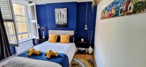 a bedroom with blue walls and two beds with yellow pillows at Double Bed at Cozy Hailsham in London