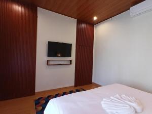 a bedroom with a bed and a flat screen tv at Pondok Layung in Tegalalang