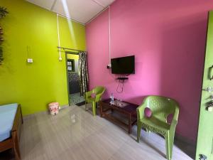 a room with pink and green walls and a table and chairs at New Kaziranga Cottage in Kāziranga