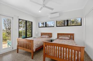 two beds in a room with windows at Moreton View @ Tangalooma in Tangalooma