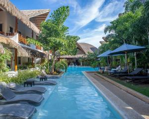 邦劳Bathala Resort的度假酒店的游泳池配有躺椅和遮阳伞