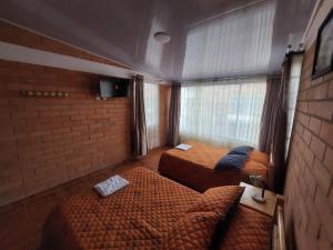 a bedroom with two beds and a brick wall at Casa Vacacional Paipa in Paipa