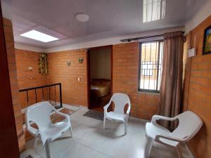 a room with three white chairs and a brick wall at Casa Vacacional Paipa in Paipa +53 photos